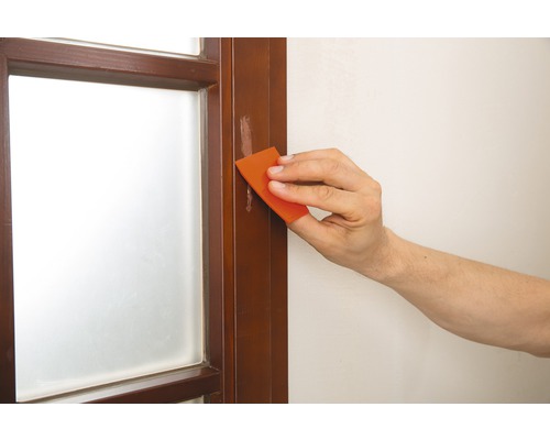 Person repariert einen Fensterrahmen mit einem Spachtel