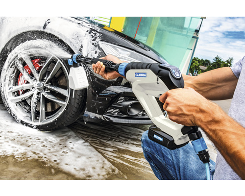Eine Person reinigt mit einem Gloria Akku-Hochdruckreiniger ein Auto.