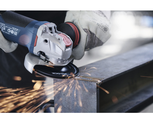 Eine Person benutzt einen Winkelschleifer an einem Metallstück, Funken fliegen.