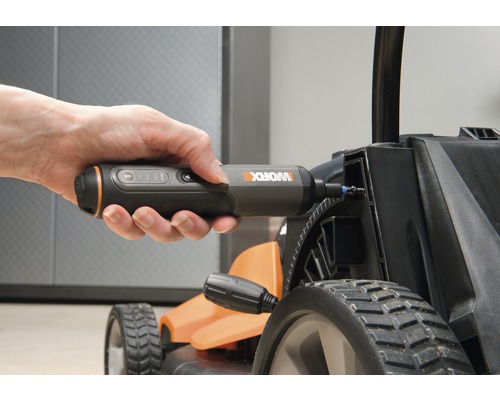 Eine Hand hält einen Akku-Schraubendreher, der an einem Rasenmäher verwendet wird.