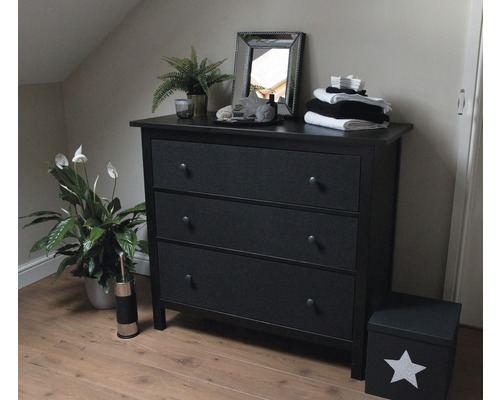 Schlafzimmer mit schwarzer Kommode mit drei Schubladen, Spiegel und Zimmerpflanzen