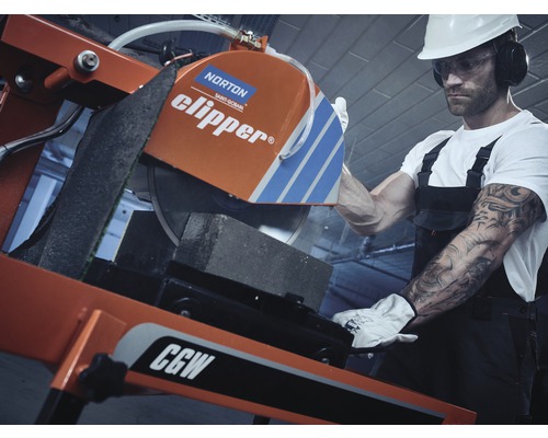 Ein Bauarbeiter schneidet mit einer Steinsäge einen Stein.