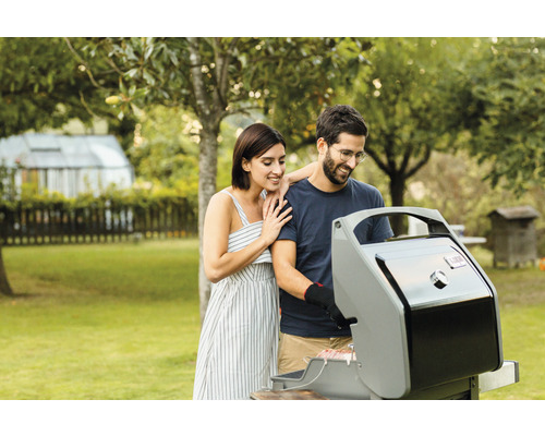 Ein Paar grillt in einem Garten mit einem Gasgrill