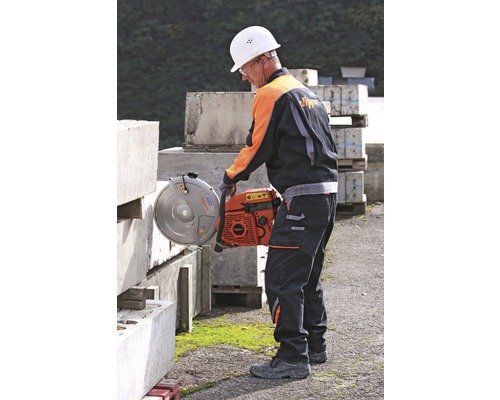 Ein Mann mit Schutzhelm und Schutzbrille schneidet mit einer Steinsäge einen Steinblock.