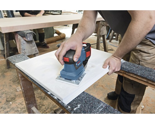 Eine Person schleift mit einem Elektroschleifer ein Werkstück.