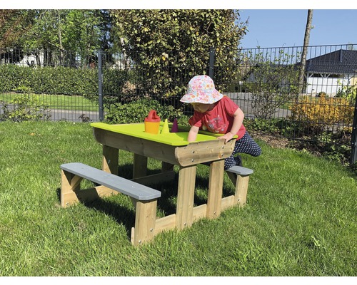 Kind spielt an Sandtisch mit Sitzbank aus Holz im Garten
