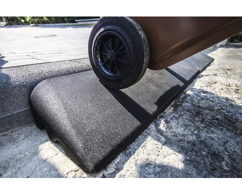 Eine Mülltonne rollt über eine Bordsteinrampe aus Gummi.