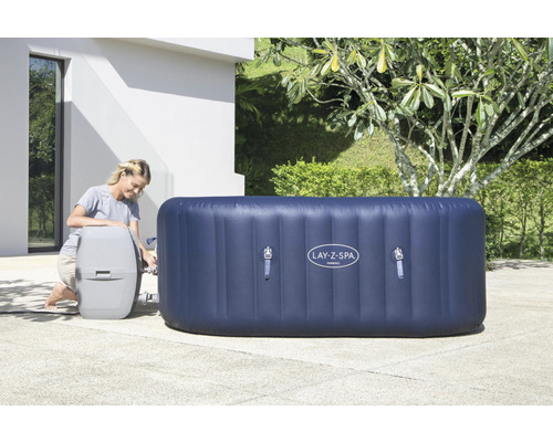 Aufblasbarer rechteckiger Lay Z Spa Whirlpool mit Frau und Pumpe im Aussenbereich.