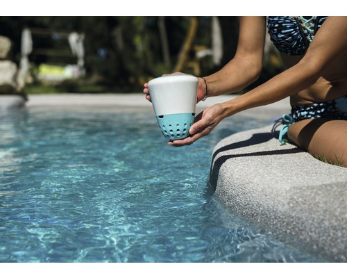 Frau hält einen Poolwasser-Desinfektor am Poolrand