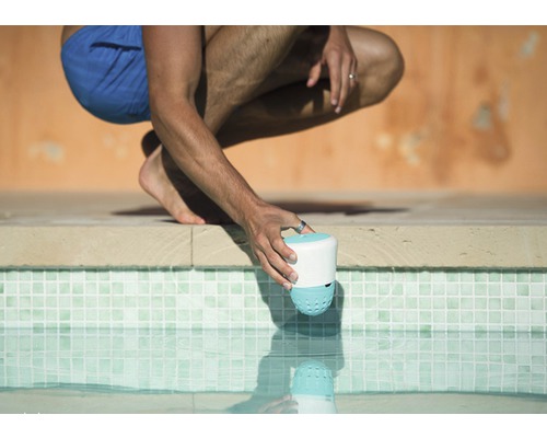 Eine Person setzt einen Poolreiniger ins Schwimmbecken.