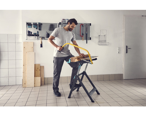 Mann sägt Holz auf einer Werkbank mit einer Metallsäge.