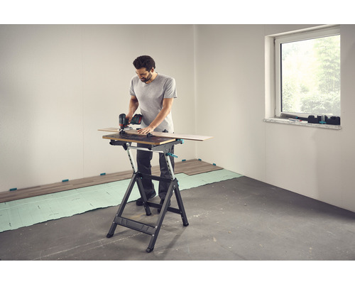 Ein Mann schneidet Laminat auf einem Arbeitstisch mit einer Handkreissäge.