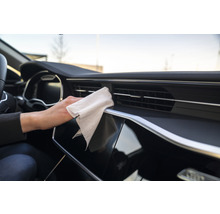 Innenraum eines Autos mit einer Person, die ein Armaturenbrett mit einem Tuch reinigt