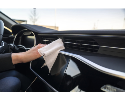 Innenraum eines Autos mit einer Person, die ein Armaturenbrett mit einem Tuch reinigt