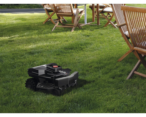 Rasenmähroboter auf Rasenfläche mit Gartenmöbeln im Hintergrund