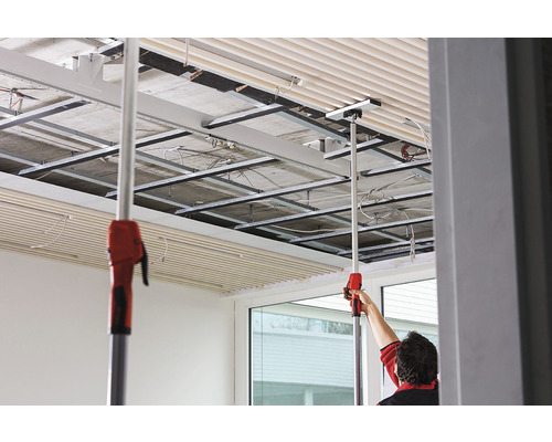 Montage von Deckenplatten mit Montagewerkzeug in einem Raum mit Deckenkonstruktion.