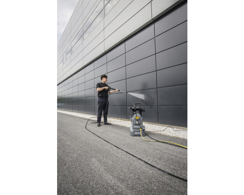 Mann reinigt Fassade mit Hochdruckreiniger.