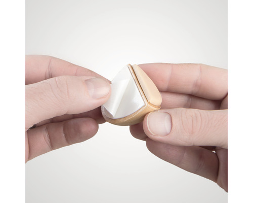 Hände entfernen Schutzfolie von einem Möbelgleiter