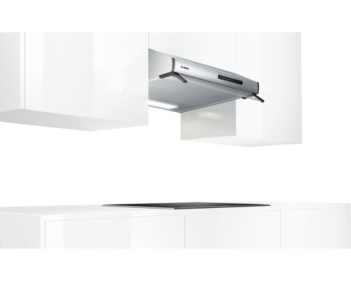 Küchenszene mit Dunstabzugshaube über einem Kochfeld, umgeben von weißen Schränken