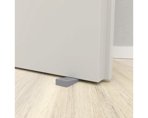 Grauer Türstopper aus Gummi vor einer Tür