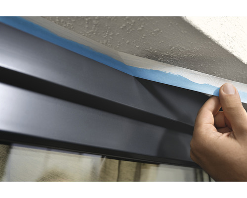 Abkleben einer Fensterscheibe mit Malerkrepp vor Malerarbeiten.