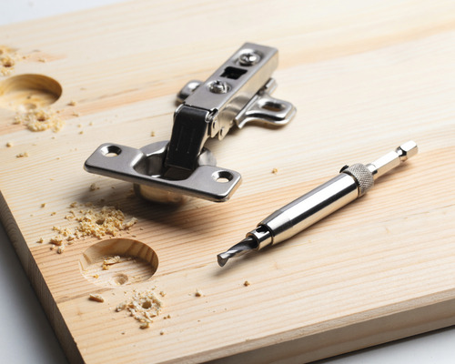 Möbelscharnier, Holzbohrer und Holzbrett mit Bohrlöchern