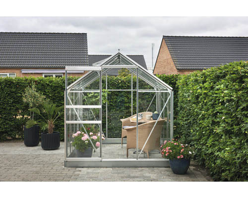 Gewächshaus mit Pflanzen und Sitzgelegenheit im Garten