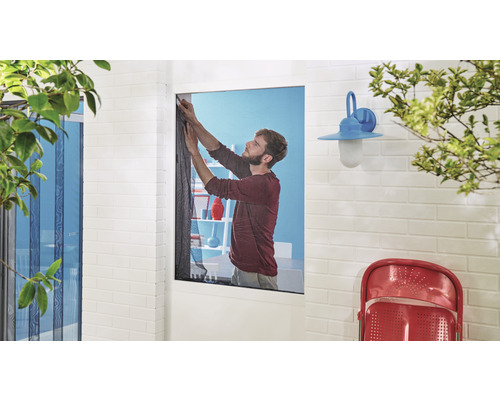 Mann montiert ein Insektenschutzgitter am Fenster