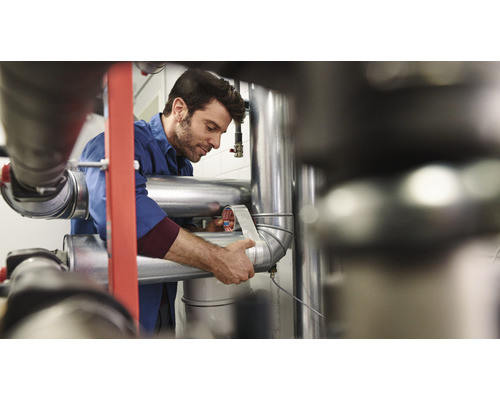 Ein Mann umwickelt ein Rohr mit Dichtungsband.