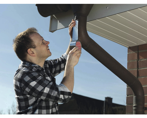 Ein Mann repariert eine Dachrinne mit Dichtband.