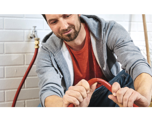 Mann repariert einen undichten Wasserschlauch