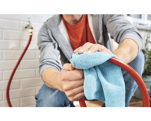 Eine Person reinigt einen Gartenschlauch mit einem Tuch.