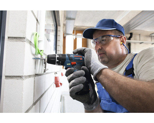 Handwerker bohrt mit einem Akku-Bohrschrauber in eine Wand