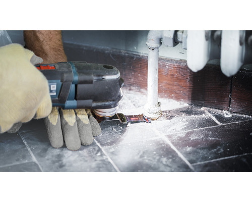 Bediener mit Multitool bei Renovierungsarbeiten in Bad