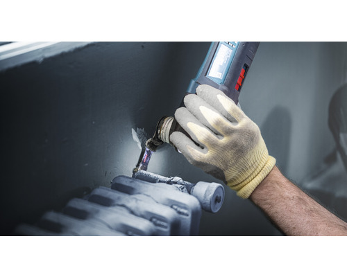 Handwerker benutzt Multifunktionswerkzeug am Heizkörper