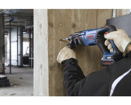 Ein Bediener bohrt mit einem Bohrhammer in eine Betonwand.