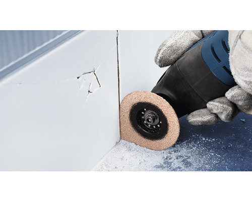 Eine Person verwendet ein Multifunktionswerkzeug zum Entfernen von beschädigten Fliesenfugen.