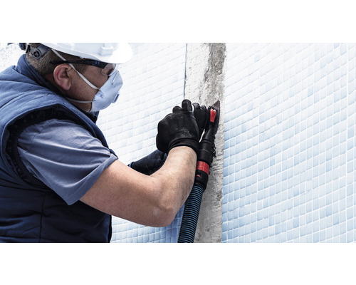 Handwerker mit persönlicher Schutzausrüstung bei der Fliesenfugenbearbeitung