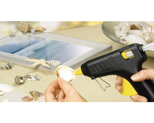 Heißklebepistole beim Anbringen einer Muschel auf einem Bilderrahmen