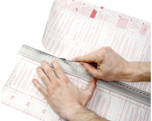 Zuschneiden einer selbstklebenden Folie mit Messer und Lineal