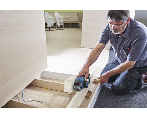 Handwerker hobelt Holz mit einem Elektrohobel