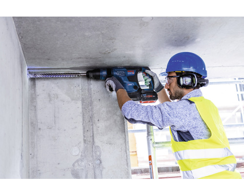Handwerker bohrt mit Bohrhammer in eine Betondecke