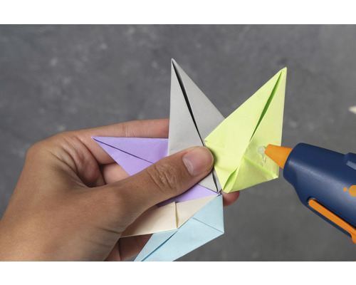 Person klebt Origami Stern mit Heißklebepistole