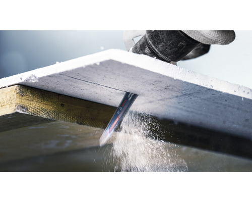 Eine Stichsäge schneidet eine Gipsfaserplatte auf einem Holzrahmen.