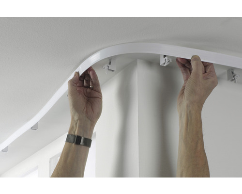 Person montiert eine flexible Gardinenschiene an der Decke