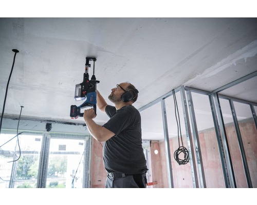 Mann bohrt mit einem Bohrhammer ein Loch in die Decke