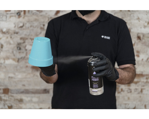 Eine Person sprüht mit Kunststoffgrundierung auf einen Blumentopf.