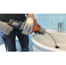 Person verwendet eine elektrische Rohrreinigungsspirale im Waschbecken, um eine Verstopfung zu lösen.