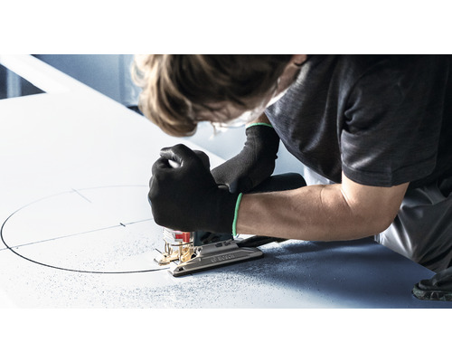 Eine Person sägt mit einer Stichsäge einen Kreis in eine Platte.