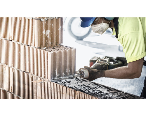 Ein Arbeiter schneidet einen Ziegelstein mit einem Fuchsschwanz